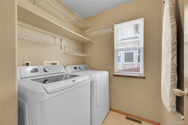 laundry room with separate washer and dryer, light tile patterned floors, and a healthy amount of sunlight