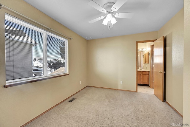 unfurnished bedroom featuring ceiling fan, light colored carpet, connected bathroom, and sink