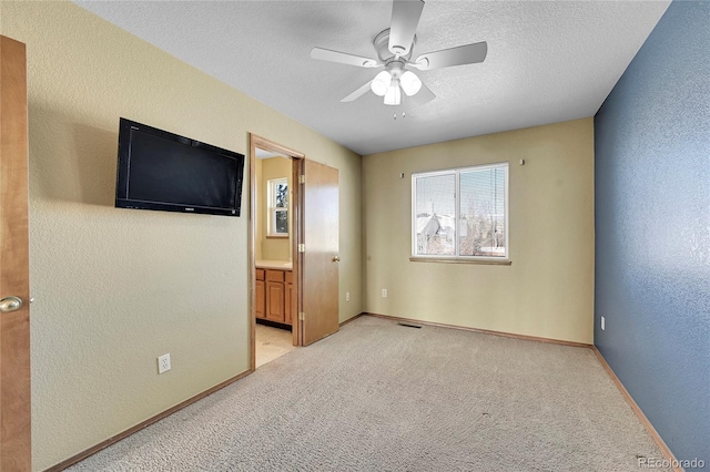 empty room featuring ceiling fan, light colored carpet, and a textured ceiling