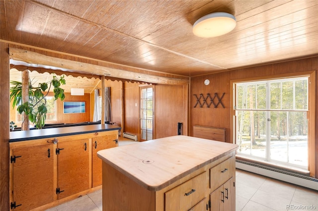 kitchen with a center island, wooden ceiling, baseboard heating, and wood walls