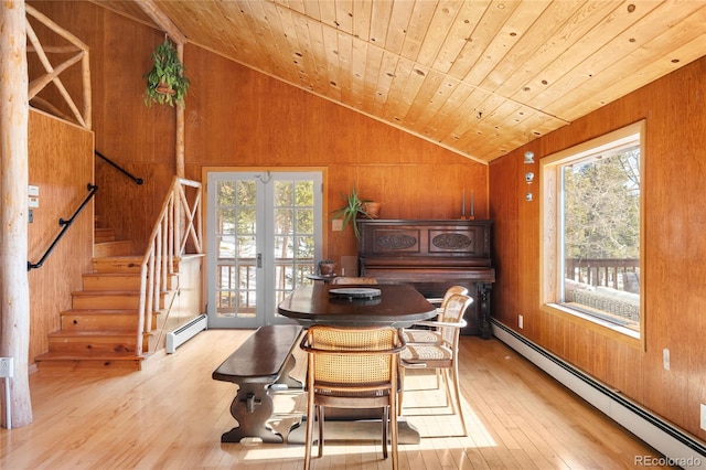 dining area featuring a baseboard radiator, vaulted ceiling, and wood walls