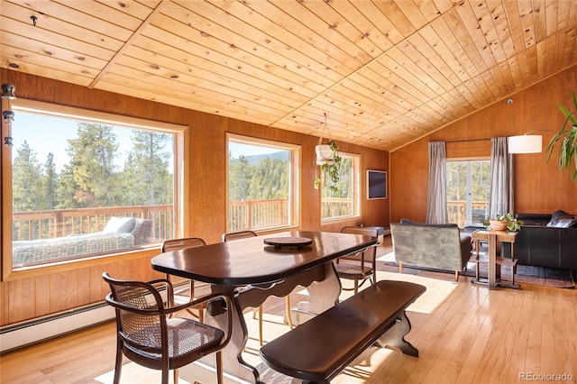 dining space featuring wood ceiling, a baseboard heating unit, light hardwood / wood-style flooring, and wood walls