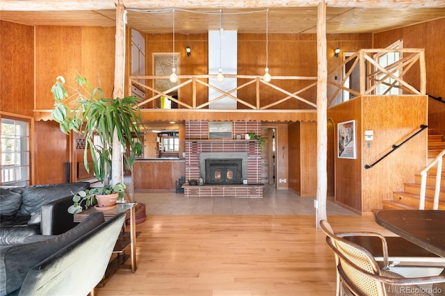 living room with hardwood / wood-style flooring, wooden walls, a wood stove, and a towering ceiling