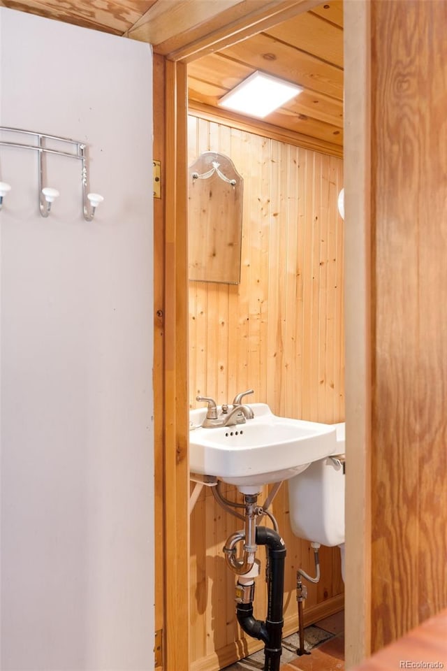 bathroom with wood ceiling, sink, and wood walls