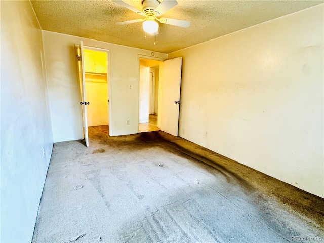 8826 E Florida Ave Unit 102, Denver, CO 80247 - unfurnished bedroom featuring a closet, a textured ceiling, ceiling fan, carpet flooring, and a walk in closet