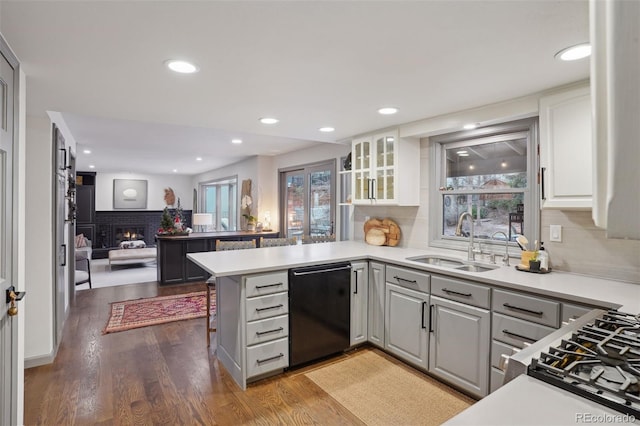 kitchen featuring kitchen peninsula, black dishwasher, plenty of natural light, and sink