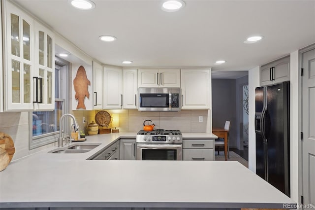 kitchen with white cabinets, sink, appliances with stainless steel finishes, tasteful backsplash, and kitchen peninsula