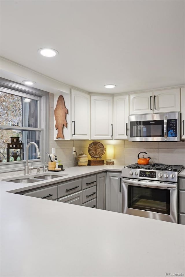 kitchen featuring decorative backsplash, sink, white cabinets, and appliances with stainless steel finishes