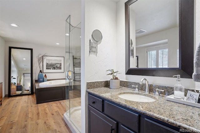 bathroom with hardwood / wood-style flooring, vanity, and separate shower and tub