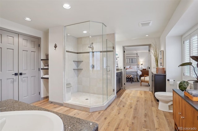 bathroom featuring sink, toilet, an enclosed shower, and hardwood / wood-style flooring