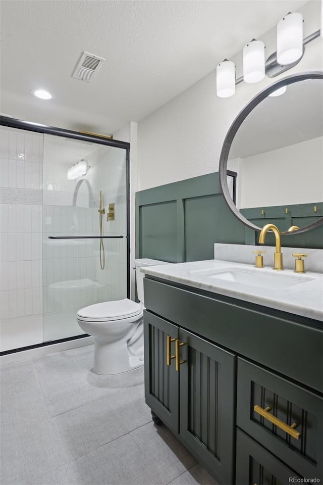 bathroom with tile patterned floors, a shower with door, vanity, and toilet