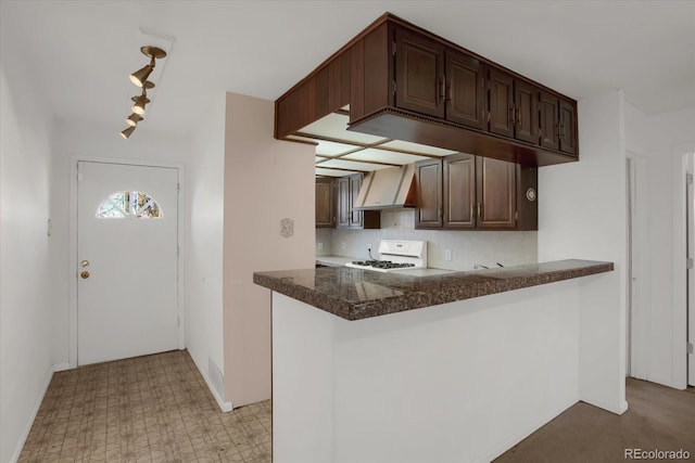 kitchen with a peninsula, wall chimney exhaust hood, range, and dark brown cabinets