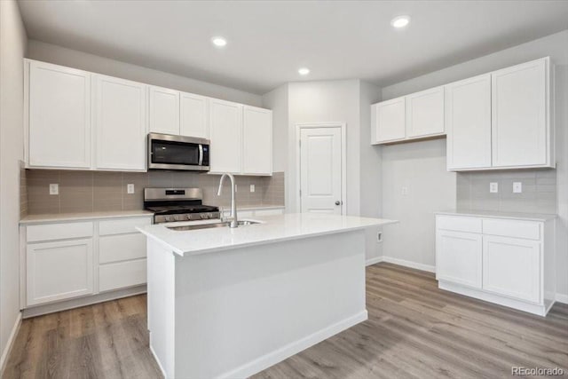 12353 E 101st Pl, Commerce City, CO 80022 - kitchen with light wood-style flooring, a sink, white cabinets, a kitchen island with sink, and appliances with stainless steel finishes
