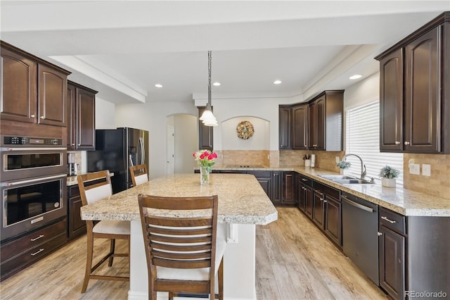 1673 Morningview Ln, Castle Rock, CO 80109 - kitchen featuring a sink, stainless steel appliances, arched walkways, dark brown cabinets, and light wood finished floors