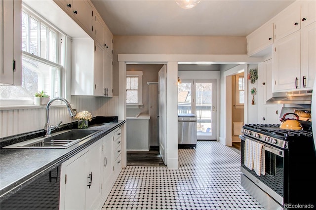 kitchen featuring dark countertops, under cabinet range hood, stainless steel gas range, and white cabinets