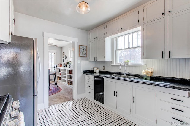 kitchen featuring dark countertops, a sink, freestanding refrigerator, and white cabinets