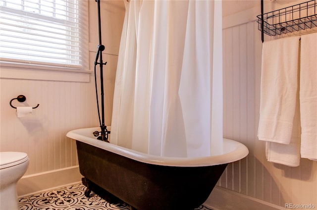 bathroom featuring a soaking tub, toilet, and tile patterned floors