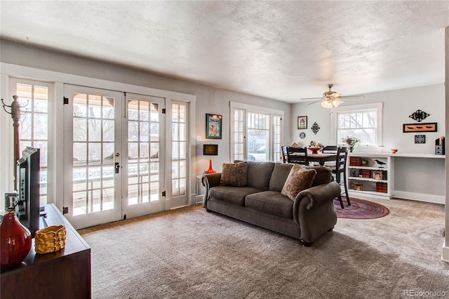 carpeted living room with a healthy amount of sunlight, baseboards, a textured ceiling, and french doors