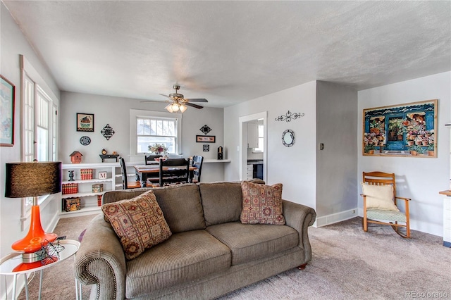 carpeted living area featuring a textured ceiling, baseboards, and a ceiling fan