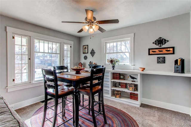 dining room featuring light carpet, a textured ceiling, a ceiling fan, and baseboards