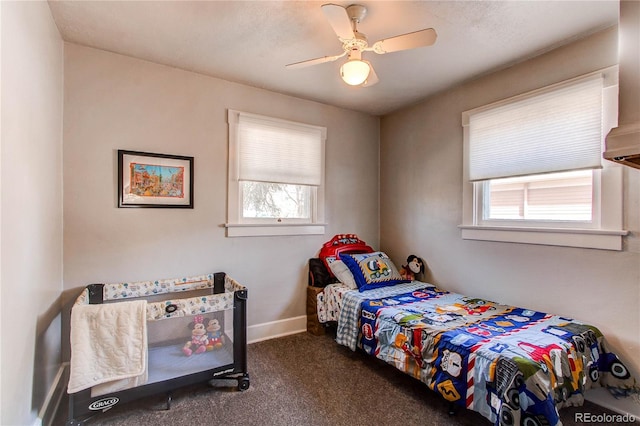 bedroom with dark colored carpet, ceiling fan, and baseboards