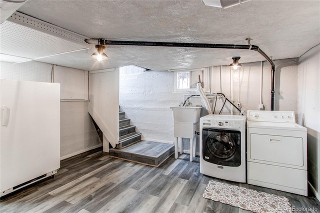 clothes washing area featuring laundry area, a textured ceiling, washer and dryer, and wood finished floors