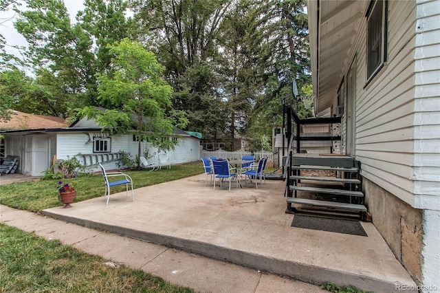 view of patio featuring fence, stairway, and an outdoor structure