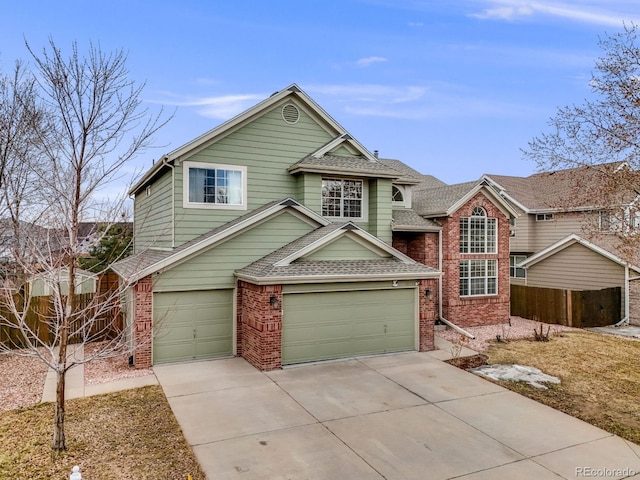 traditional-style house with brick siding, a shingled roof, an attached garage, fence, and driveway