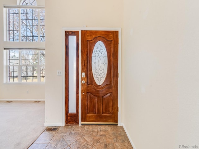 carpeted foyer entrance featuring visible vents and baseboards