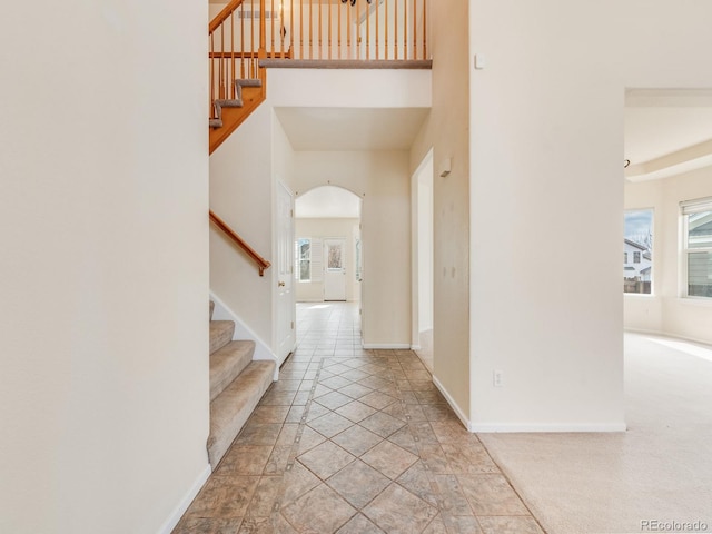 entryway with a towering ceiling, baseboards, stairway, and a wealth of natural light