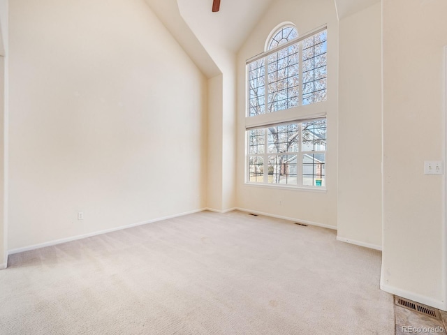 carpeted spare room with baseboards, high vaulted ceiling, and a ceiling fan