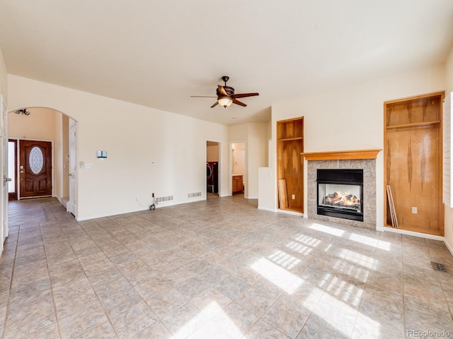 unfurnished living room featuring arched walkways, visible vents, baseboards, and a tile fireplace