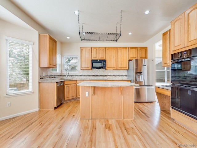 kitchen featuring black appliances, light countertops, light wood-style floors, and a center island