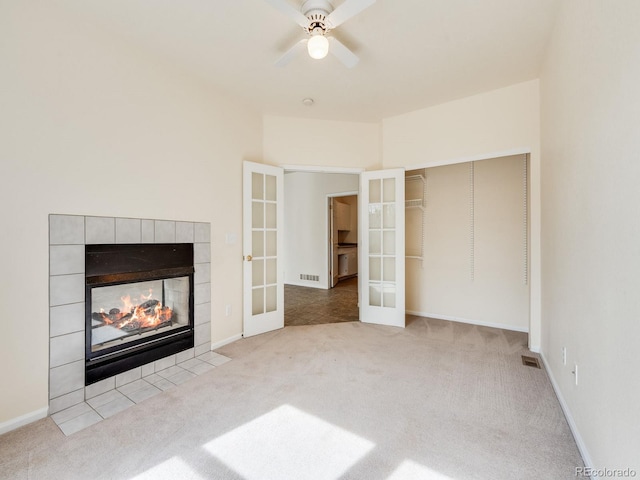 unfurnished living room with carpet floors, french doors, a fireplace, and visible vents