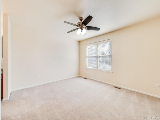 spare room with light carpet, baseboards, visible vents, and ceiling fan