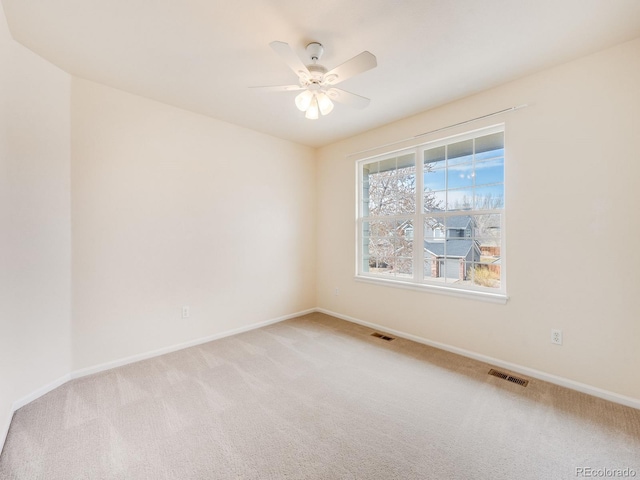 spare room with light carpet, ceiling fan, visible vents, and baseboards