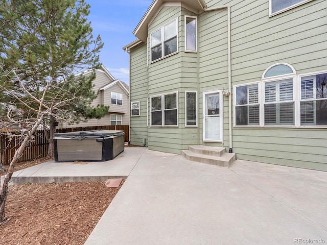 back of property with a patio area, fence, and a hot tub