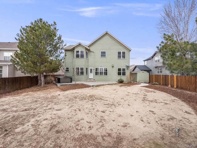 rear view of house with a hot tub, a storage shed, a patio area, a fenced backyard, and an outdoor structure