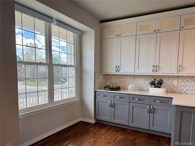 bar with tasteful backsplash, a healthy amount of sunlight, and dark wood-style floors