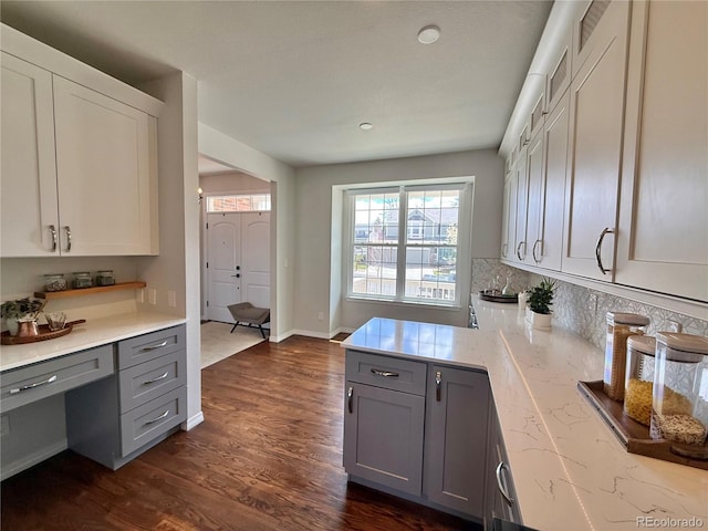 kitchen with gray cabinetry, dark wood-style floors, light stone counters, and tasteful backsplash