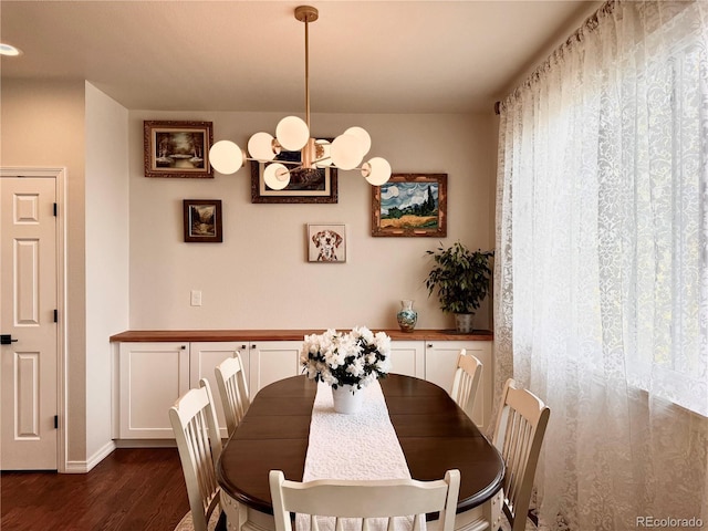 dining room featuring dark wood finished floors, baseboards, and an inviting chandelier