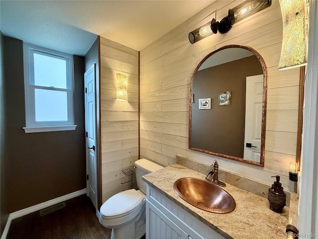 bathroom featuring toilet, baseboards, visible vents, wooden walls, and vanity
