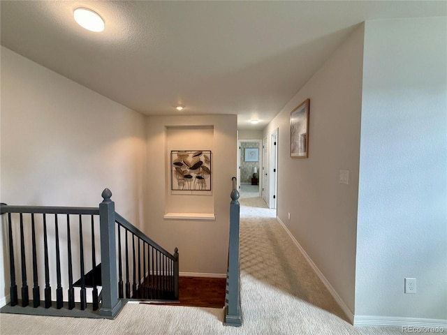 corridor with carpet floors, an upstairs landing, and baseboards