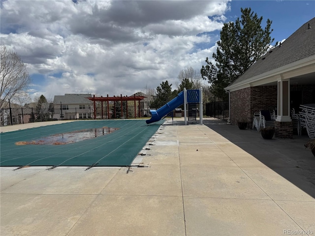 pool with playground community, a water slide, and fence