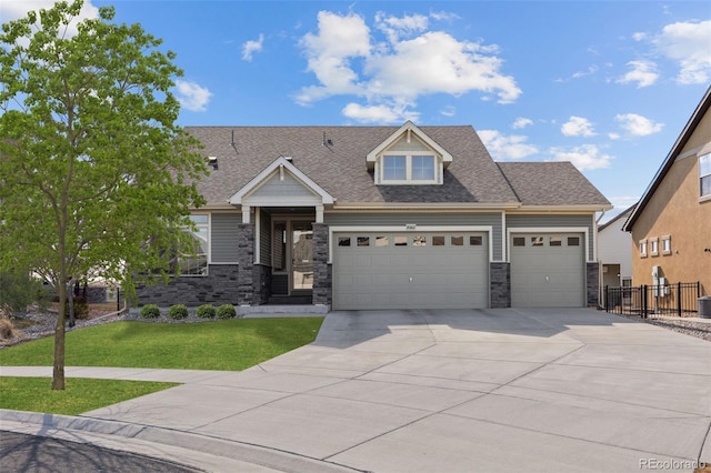 view of front facade with an attached garage, fence, driveway, stone siding, and a front yard