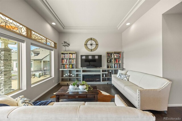 living room featuring a glass covered fireplace, recessed lighting, wood finished floors, and baseboards