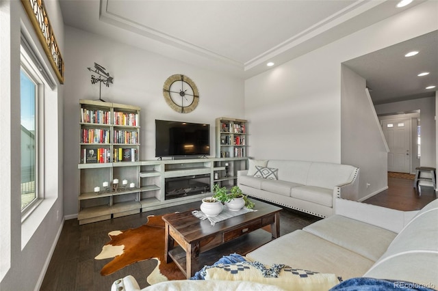 living area with a glass covered fireplace, wood finished floors, a wealth of natural light, and baseboards