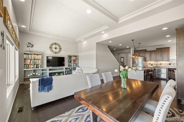 dining room featuring dark wood-style floors, visible vents, a raised ceiling, and recessed lighting