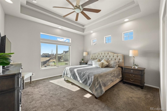 bedroom featuring baseboards, a tray ceiling, and dark carpet