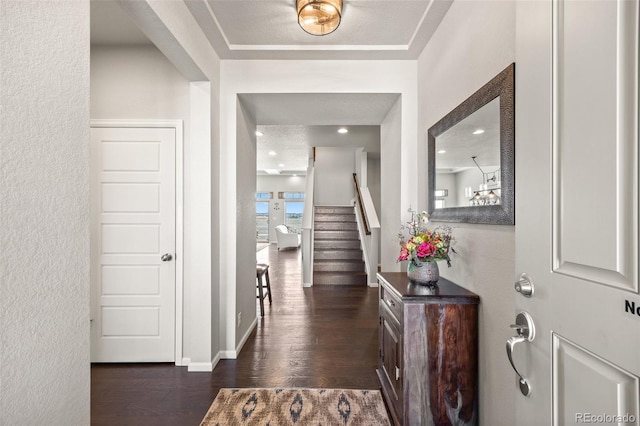 foyer entrance featuring dark wood-style flooring, baseboards, and stairs